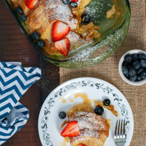 A scoopful of breakfast casserole on a plate with fruit.