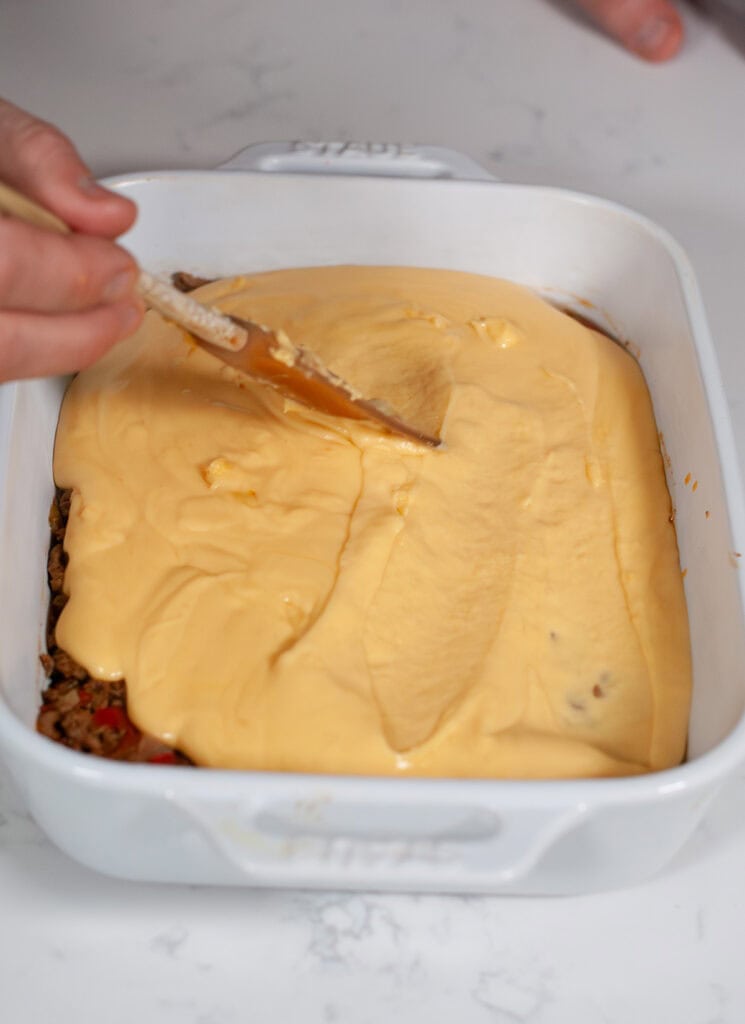 Cheese sauce spreading over the meat mixture.