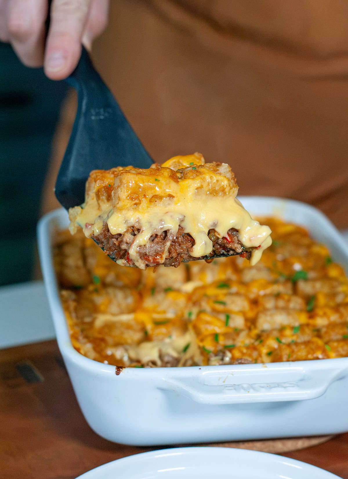 A spatula scooping tater tot casserole.