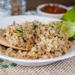 Cauliflower rice with lime wedges in a bowl.