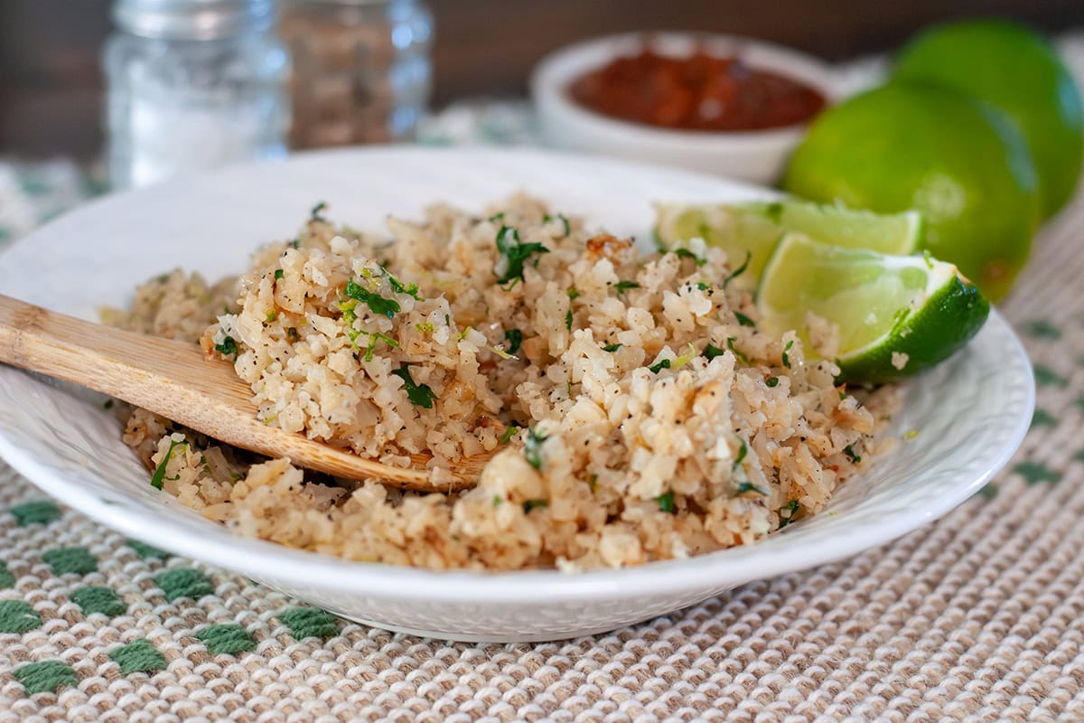 Cauliflower rice with lime wedges in a bowl.