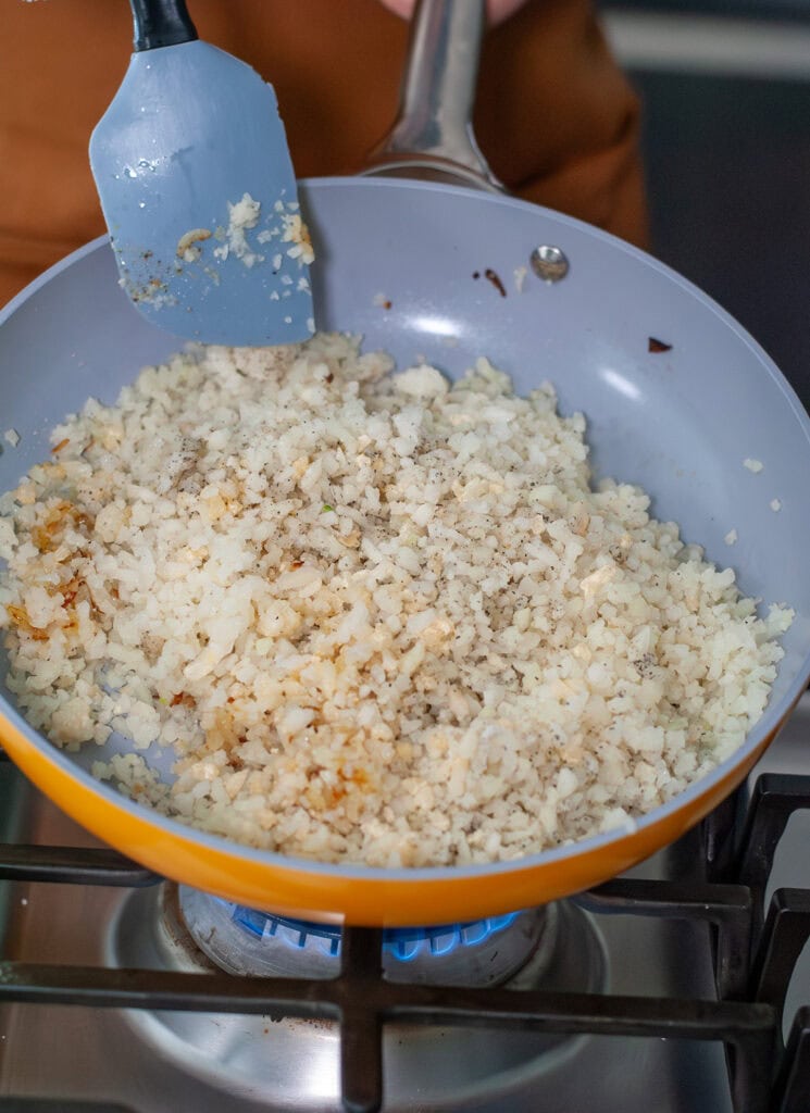 Cauliflower rice in a skillet with seasonings.