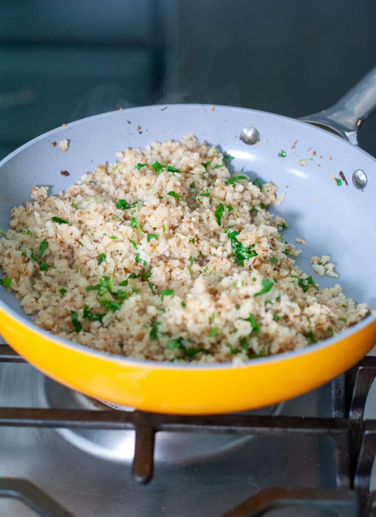 Cilantro with cauliflower rice in a skillet.