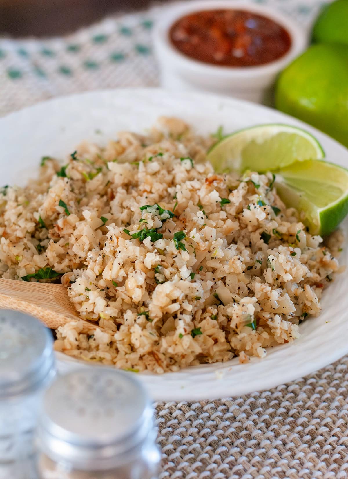 A scoop of cilantro lime cauliflower rice with lime wedges.