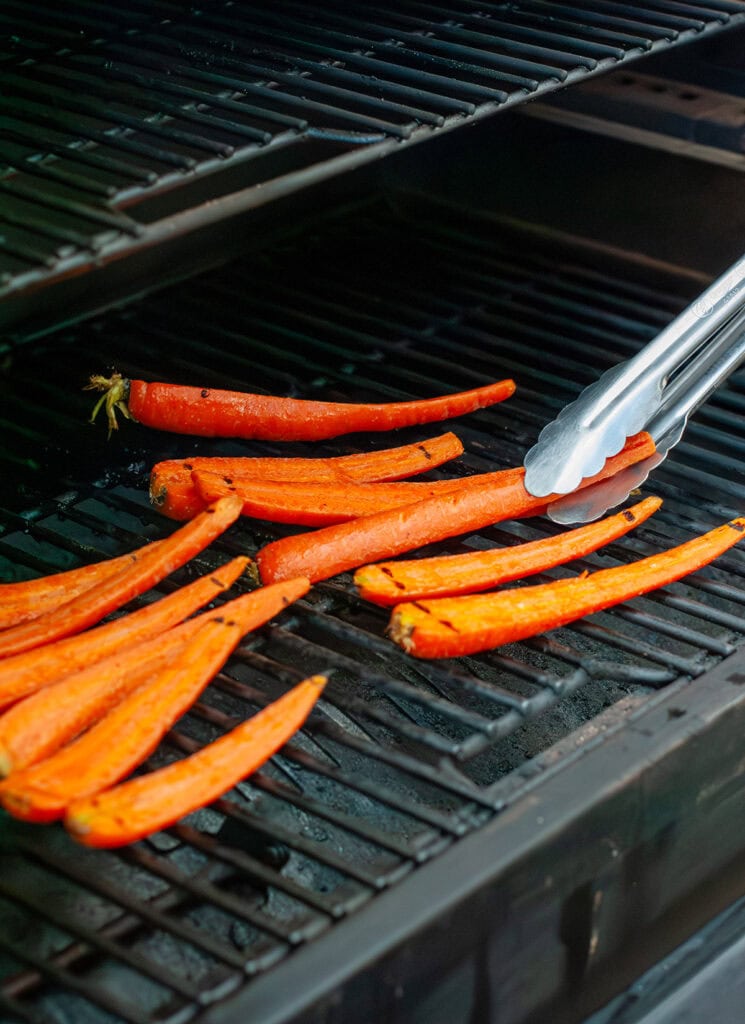 Flipping grilled carrots on the grill.