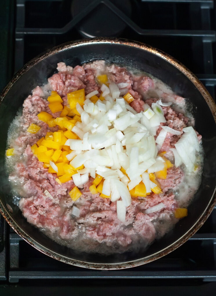 Ground turkey, peppers and onions cooking in a skillet.