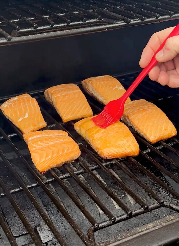A basting brush with glaze brushing onto salmon.