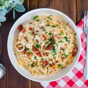 Chicken bacon ranch pasta in a bowl with cheese and parsley.