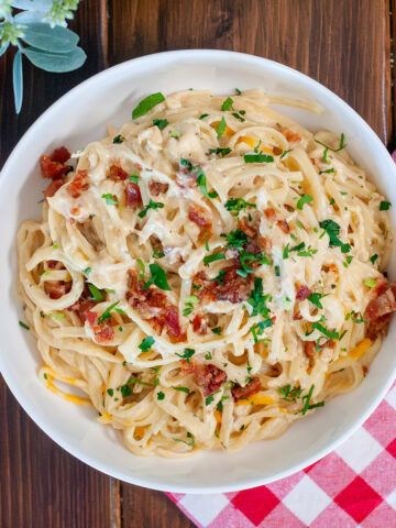 Chicken bacon ranch pasta in a bowl with cheese and parsley.