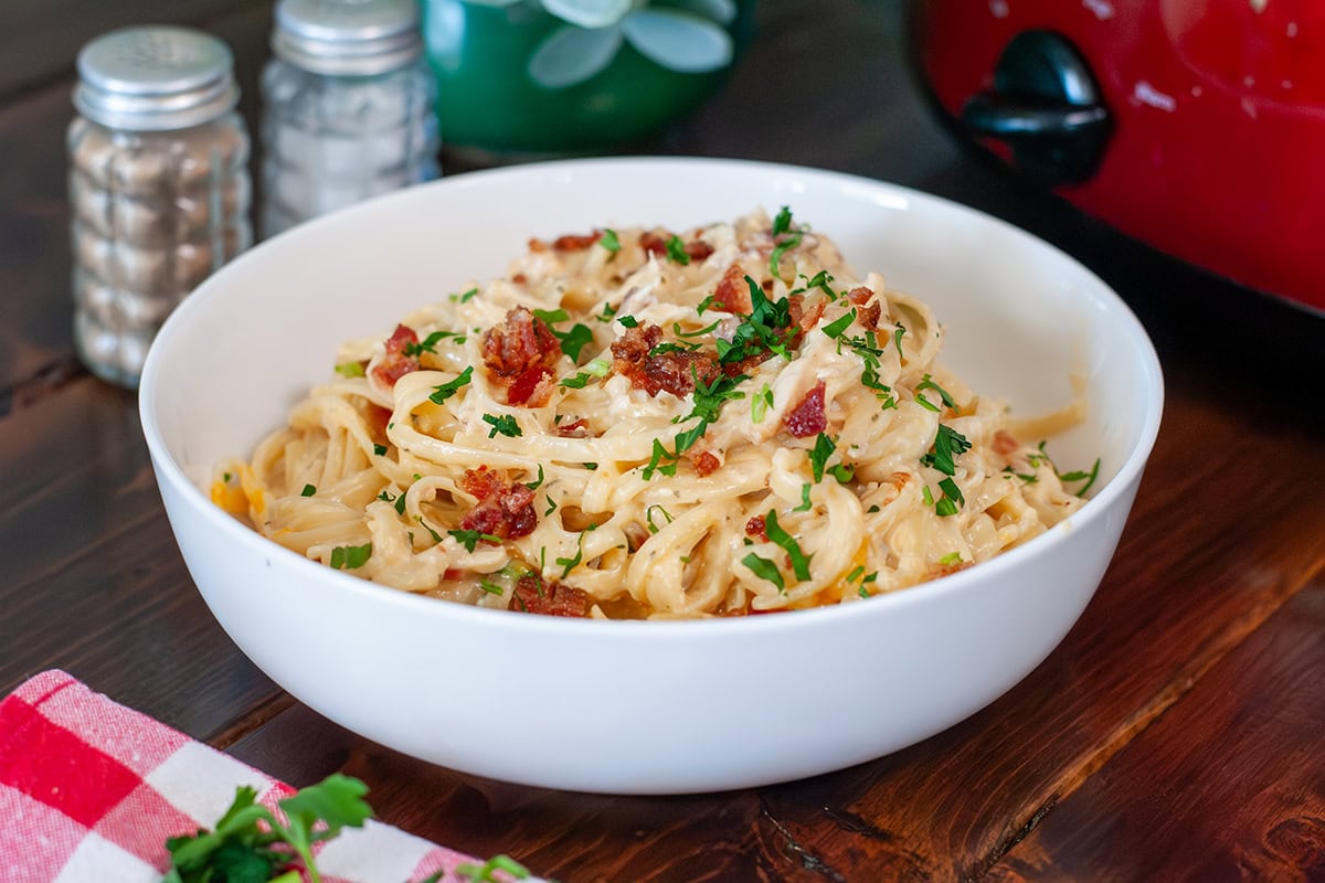 A bowl of chicken ranch bacon pasta topped with parsley.