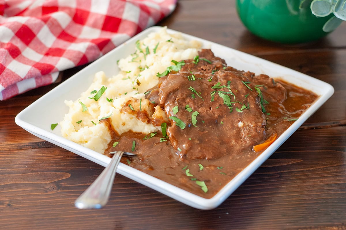 Cube steak on a plate with mashed potatoes.