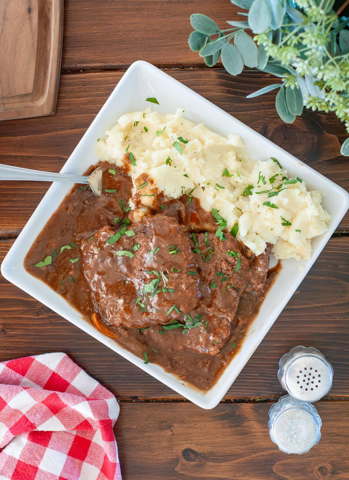 Cube Steak on a plate with mashed potatoes topped with parsley.