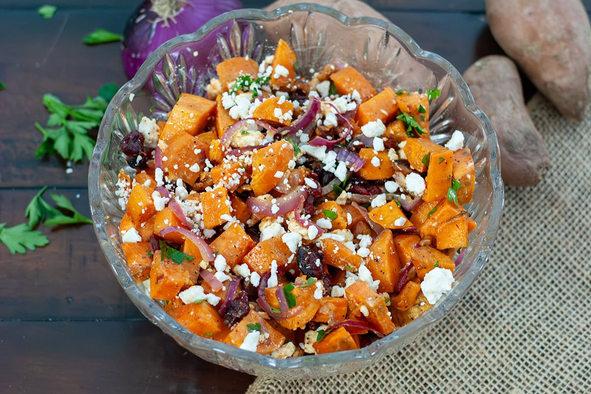 Sweet potato salad in a bowl with onions, cheese and cranberries.