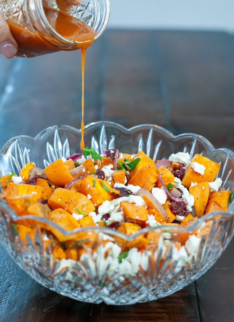 A sauce pouring over sweet potato salad.