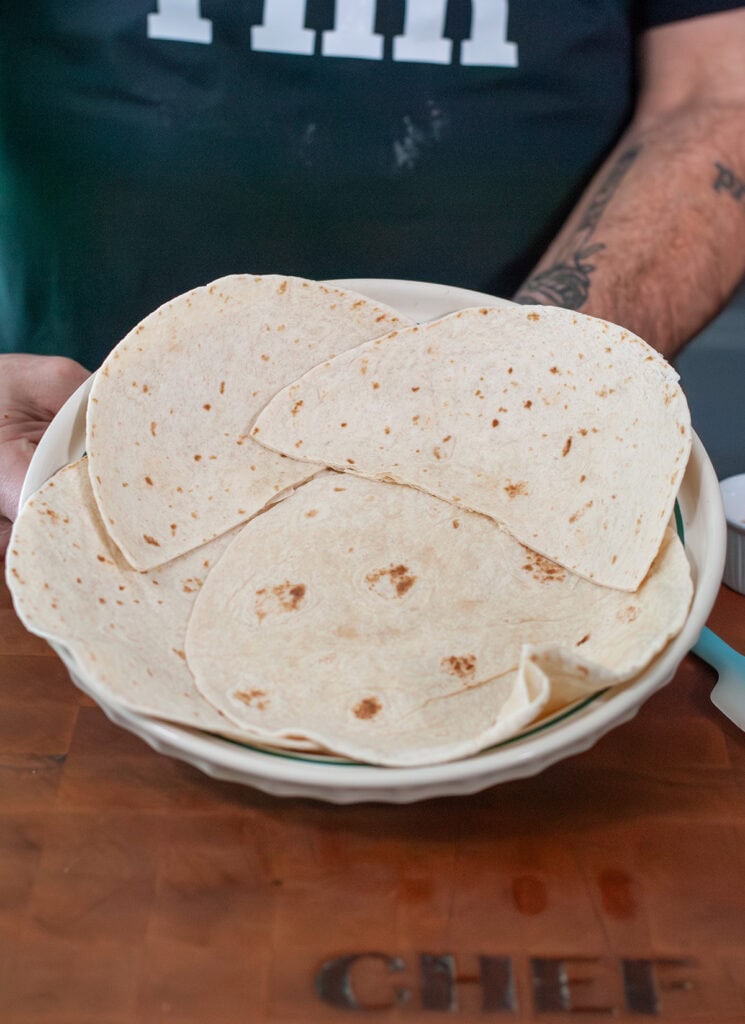 Tortillas lining the bottom of a pie dish.