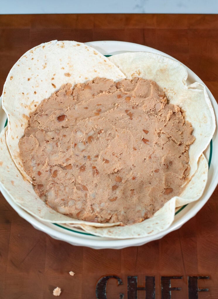 refried beans on tortillas in a pie dish.