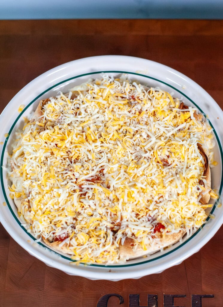 Cheese on top of tortillas in a pie dish.