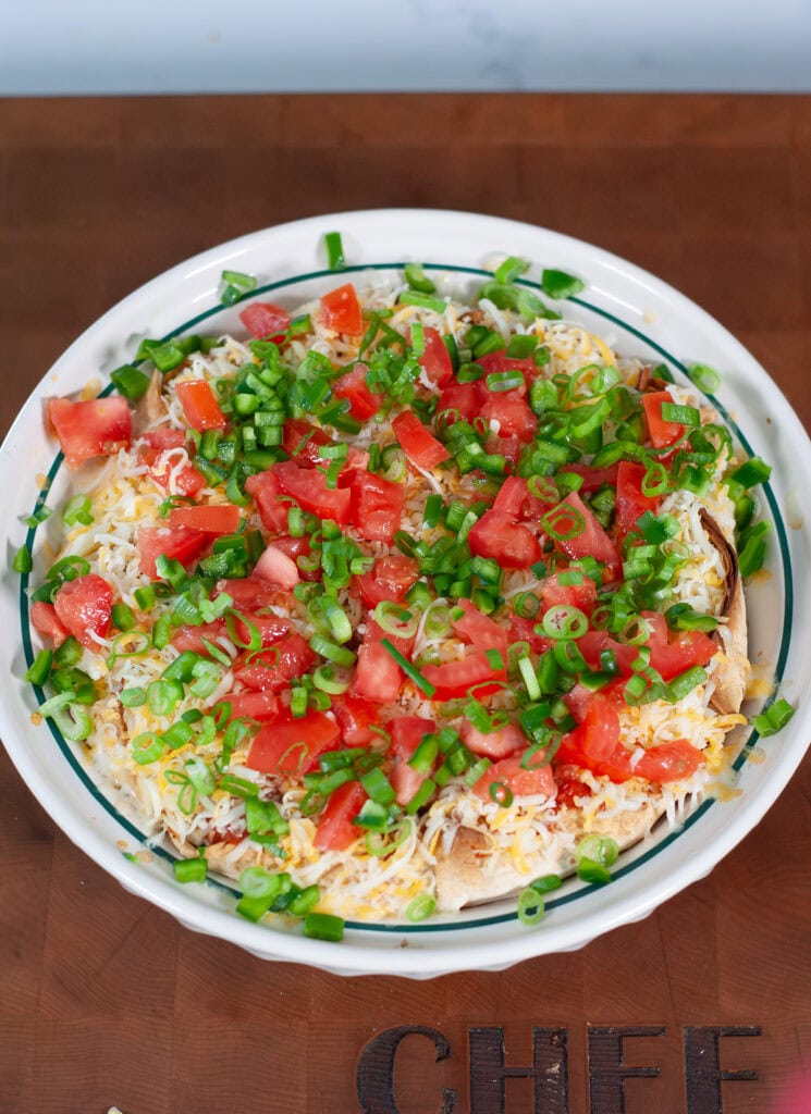 Taco pie topped with cheese tomatoes and chives.