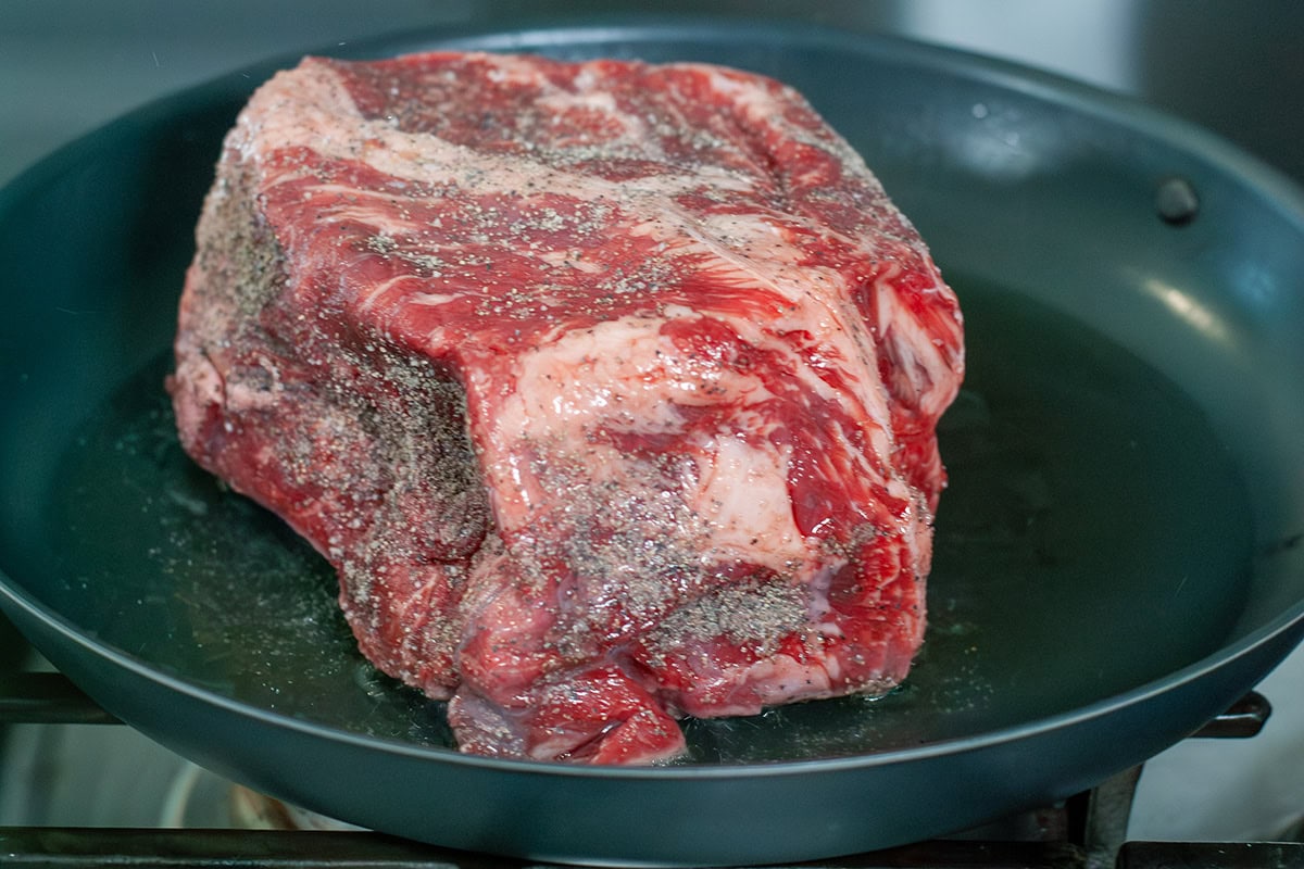 A seasoned beef chuck roast in a skillet.