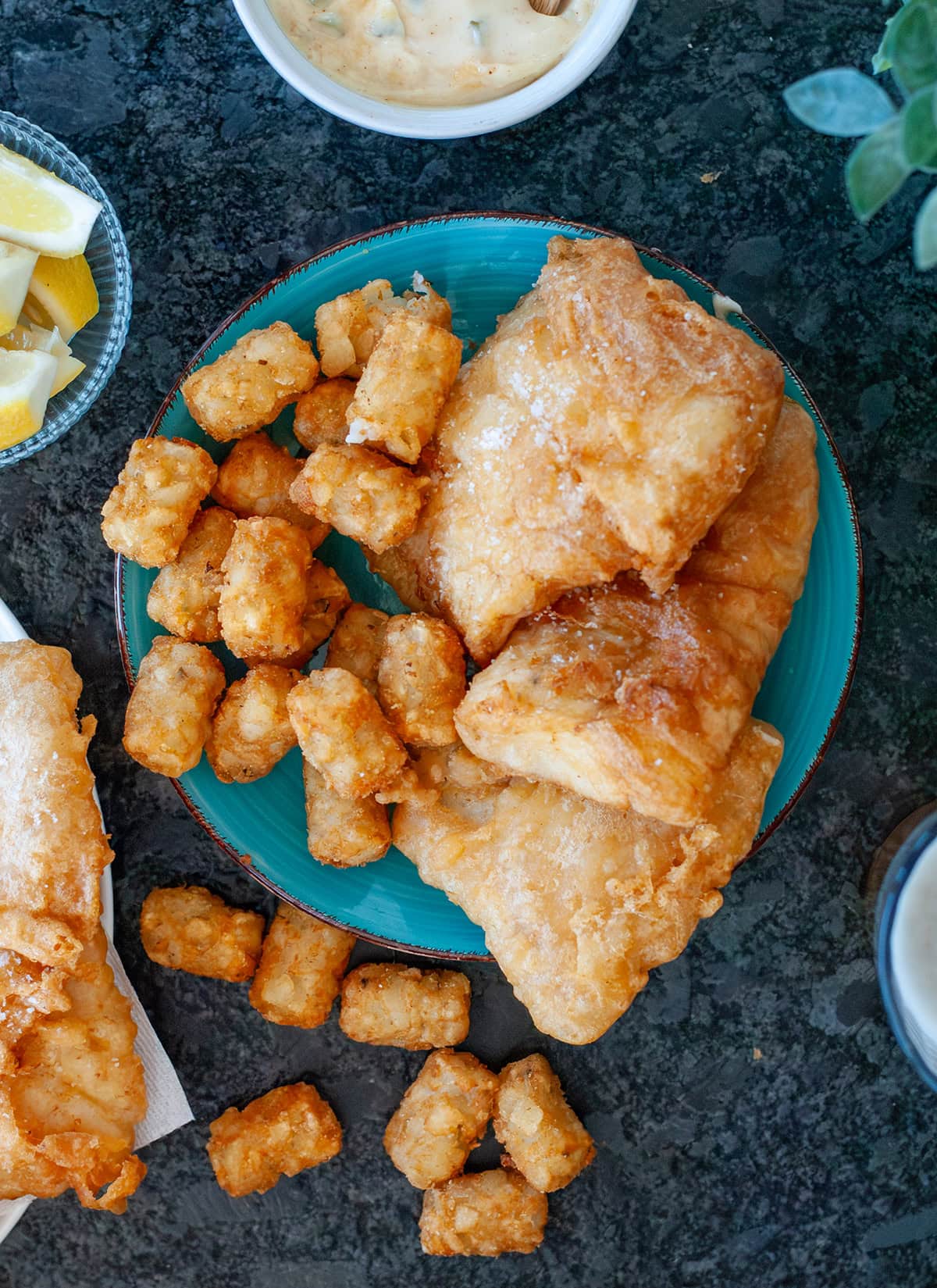A top view of a plate of golden beer battered cod showing flaky salt. 