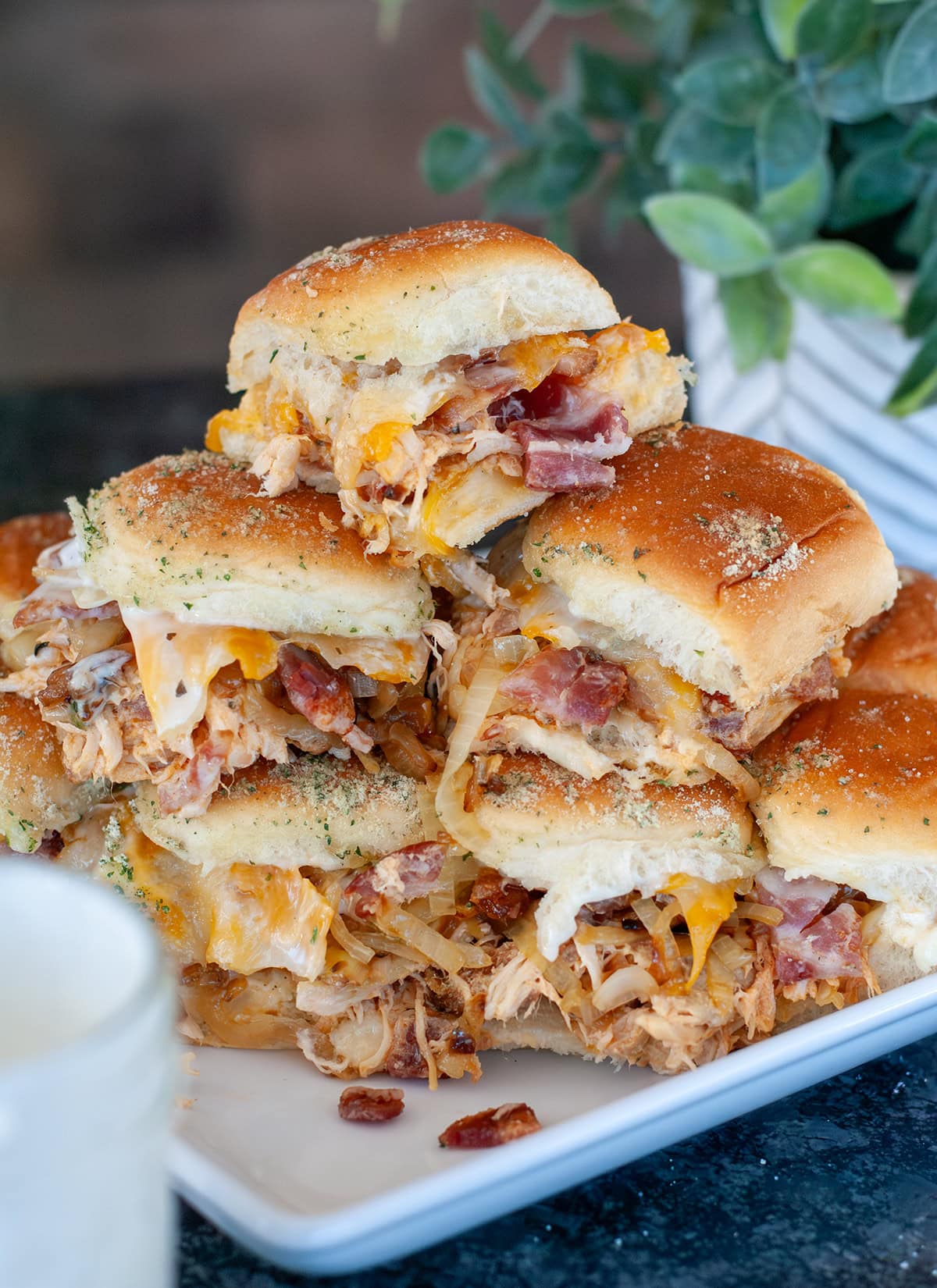 A stack of chicken bacon ranch sliders showing melty cheese. 