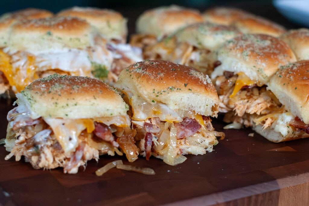 Sliders with chicken bacon and ranch on a wooden board.