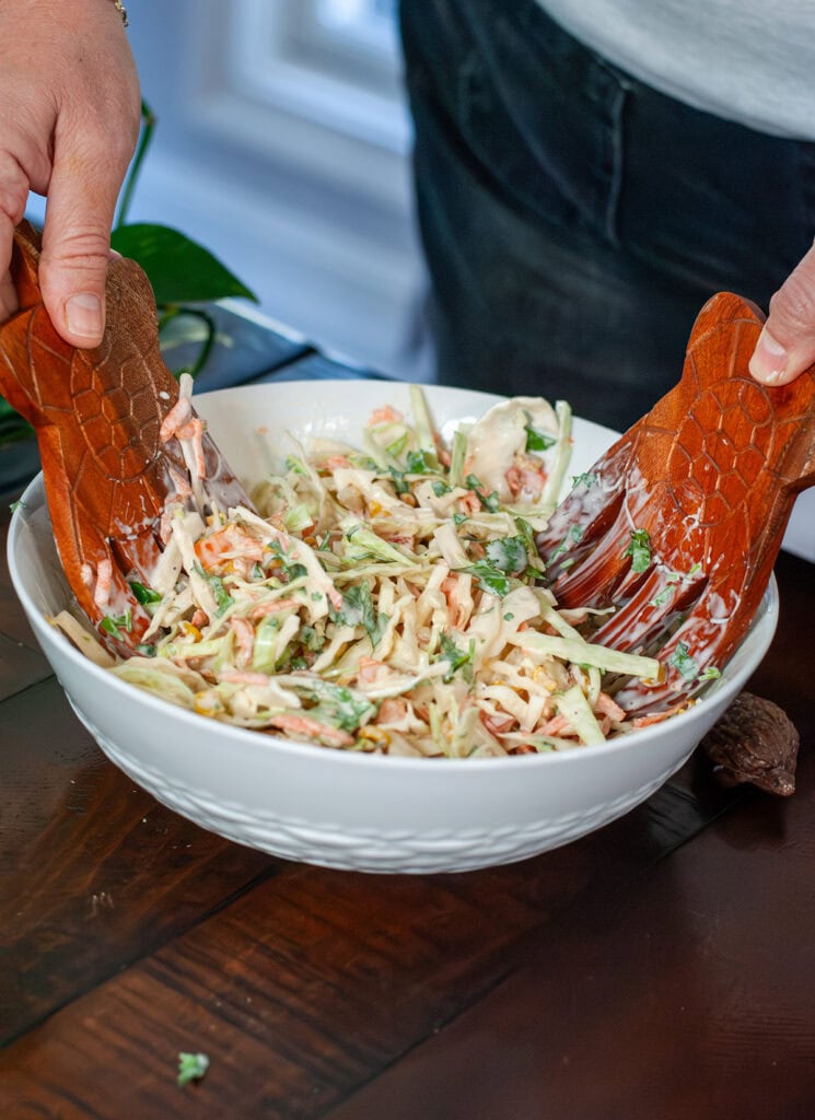 coleslaw mixing in a glass bowl.