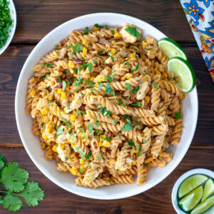 Mexican street corn pasta salad in a bowl topped with lime and cilantro.