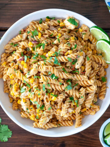 Mexican street corn pasta salad in a bowl topped with lime and cilantro.