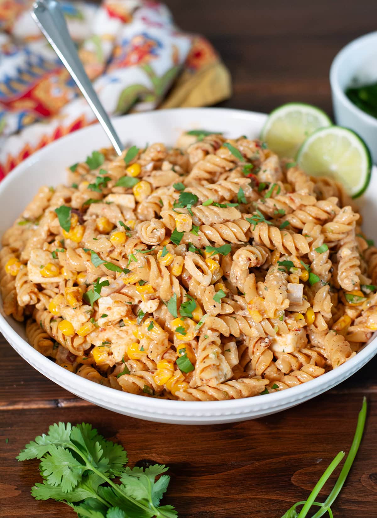 Pasta salad showing corn, chopped cilantro, and lime. 