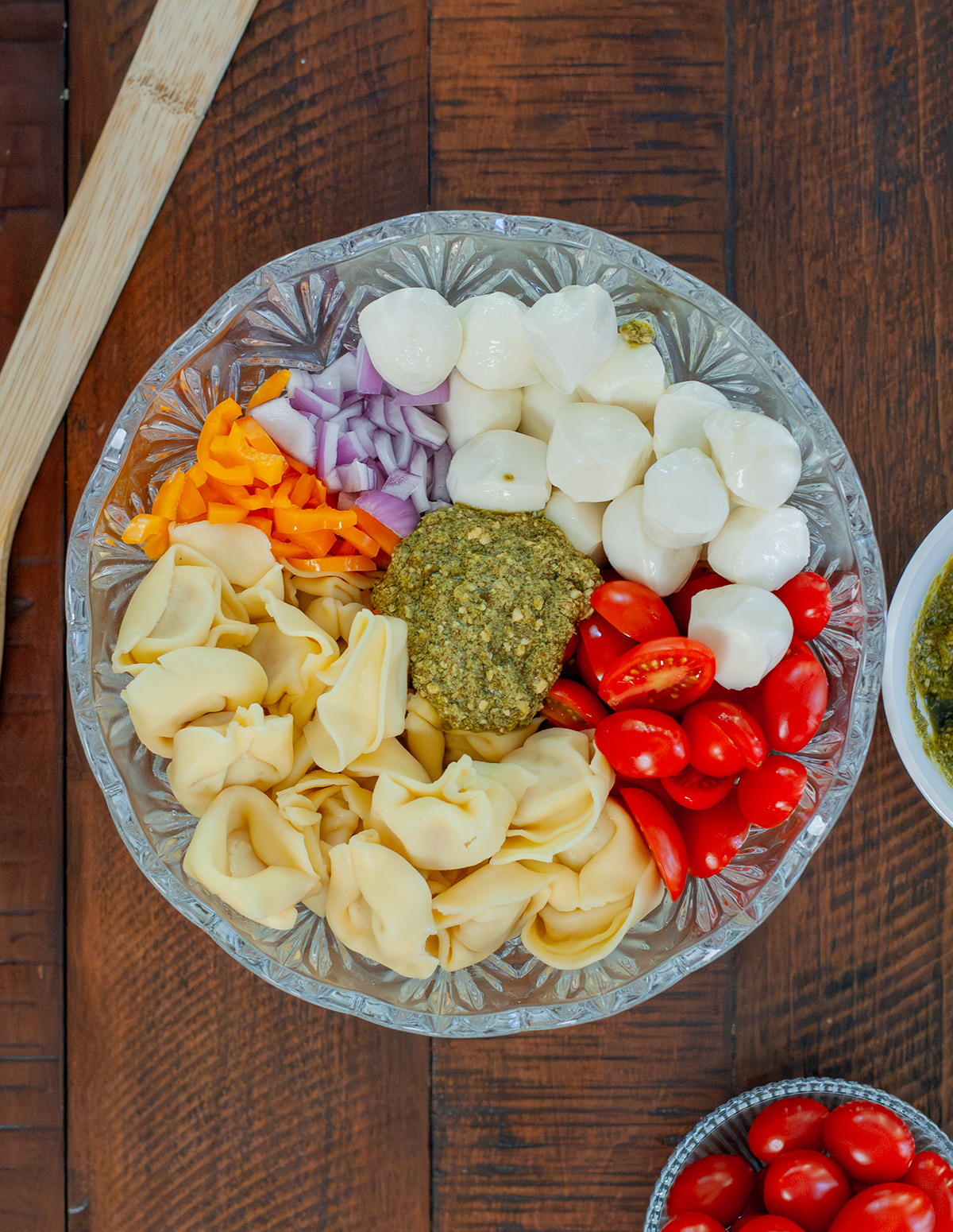 A bowl of mozzarella, onion, peppers, pesto, tomatoes and tortellini pasta.