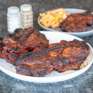 Pork Steaks on a plate with pasta salad.