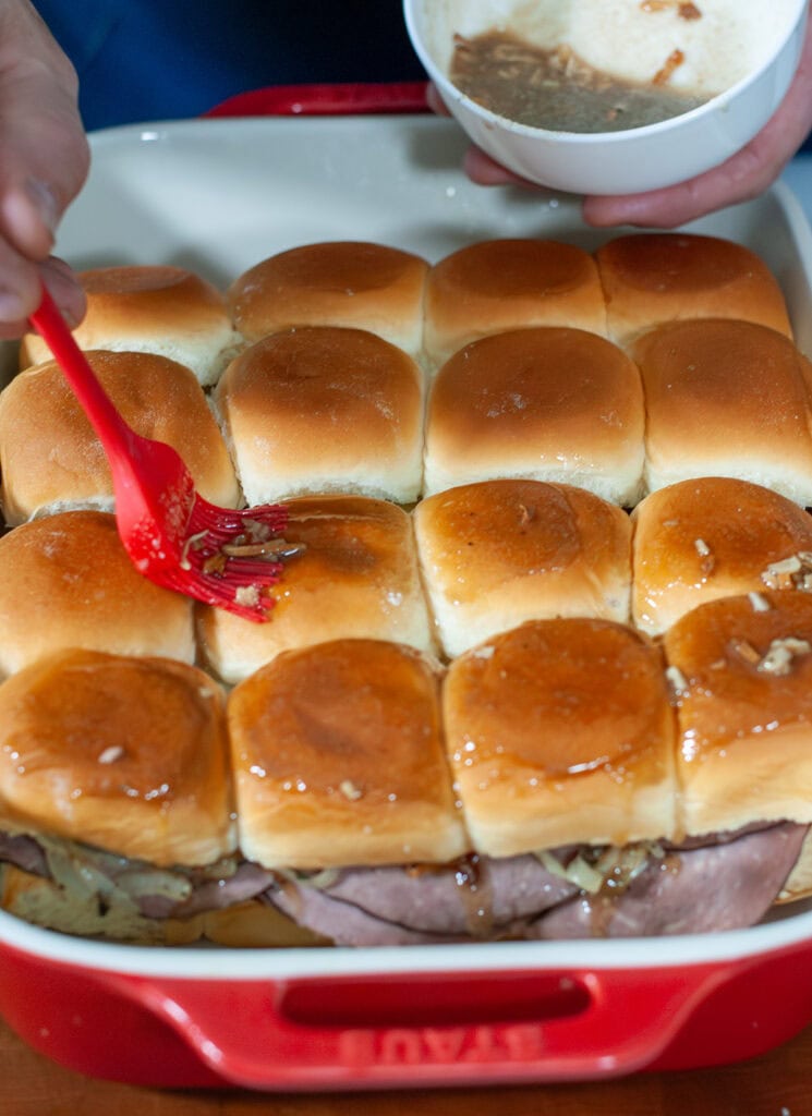 The top of the buns being brushed with the butter and onion soup mix. 
