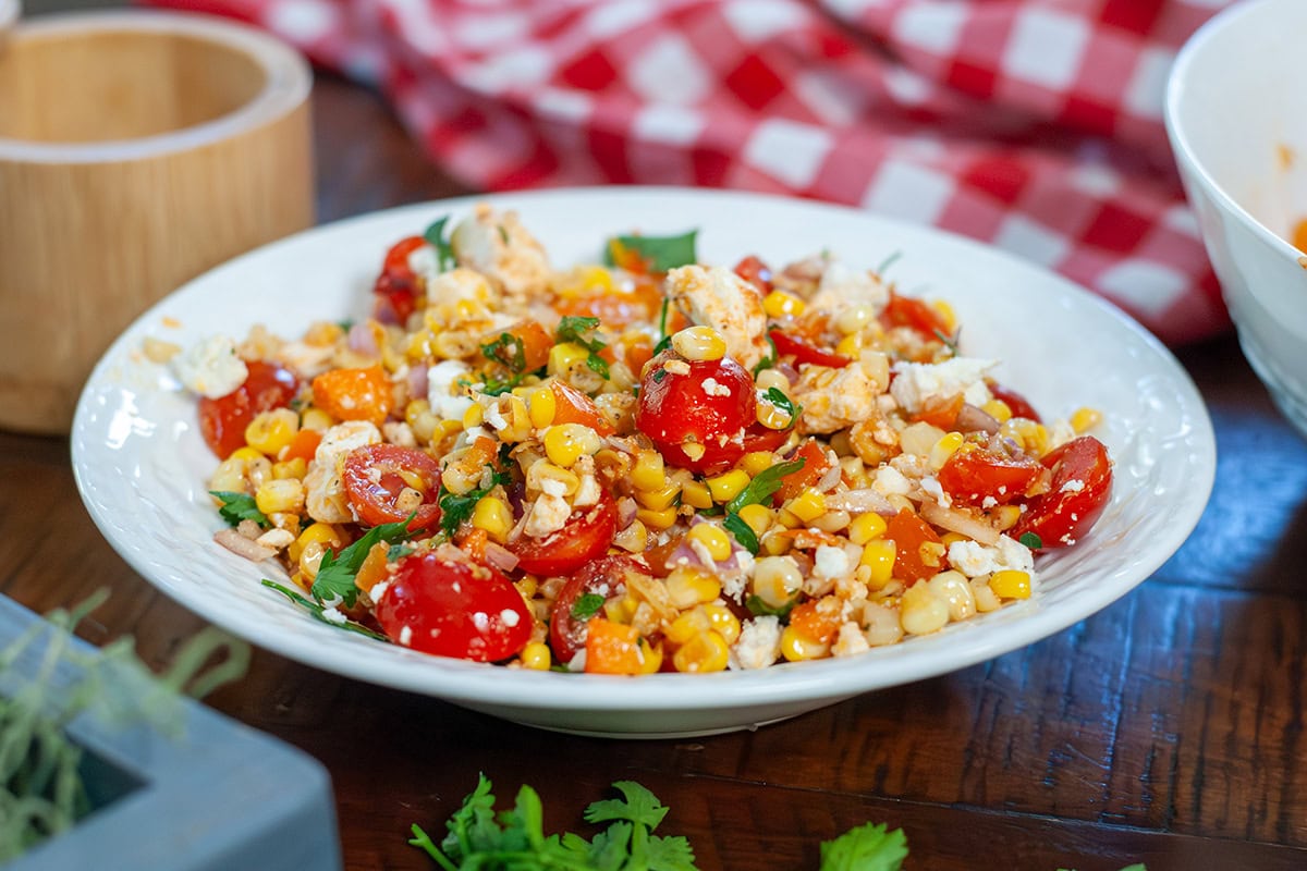 A bowl of roasted corn salad next to parsley and napkins.