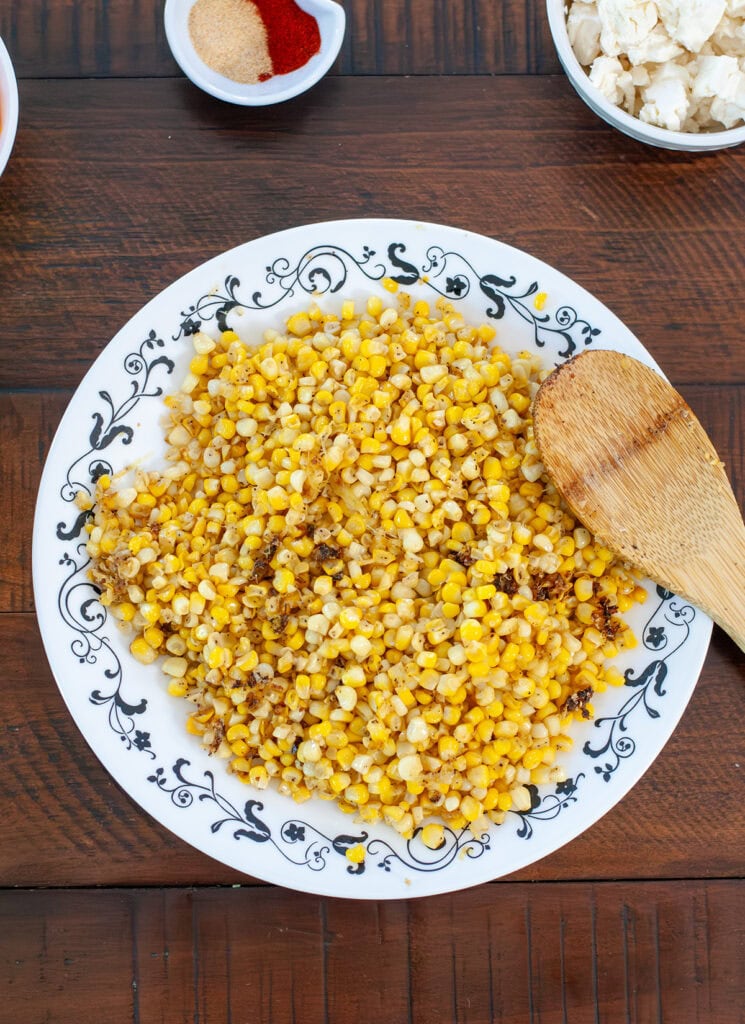 Roasted corn on a plate by seasonings.