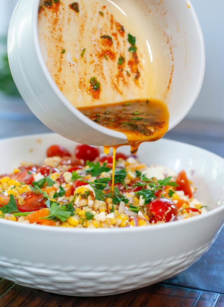 Dressing pouring over roasted corn salad.
