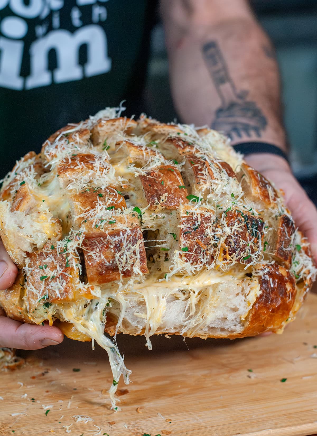 Stuffed garlic bread being pulled apart to show cheeses.