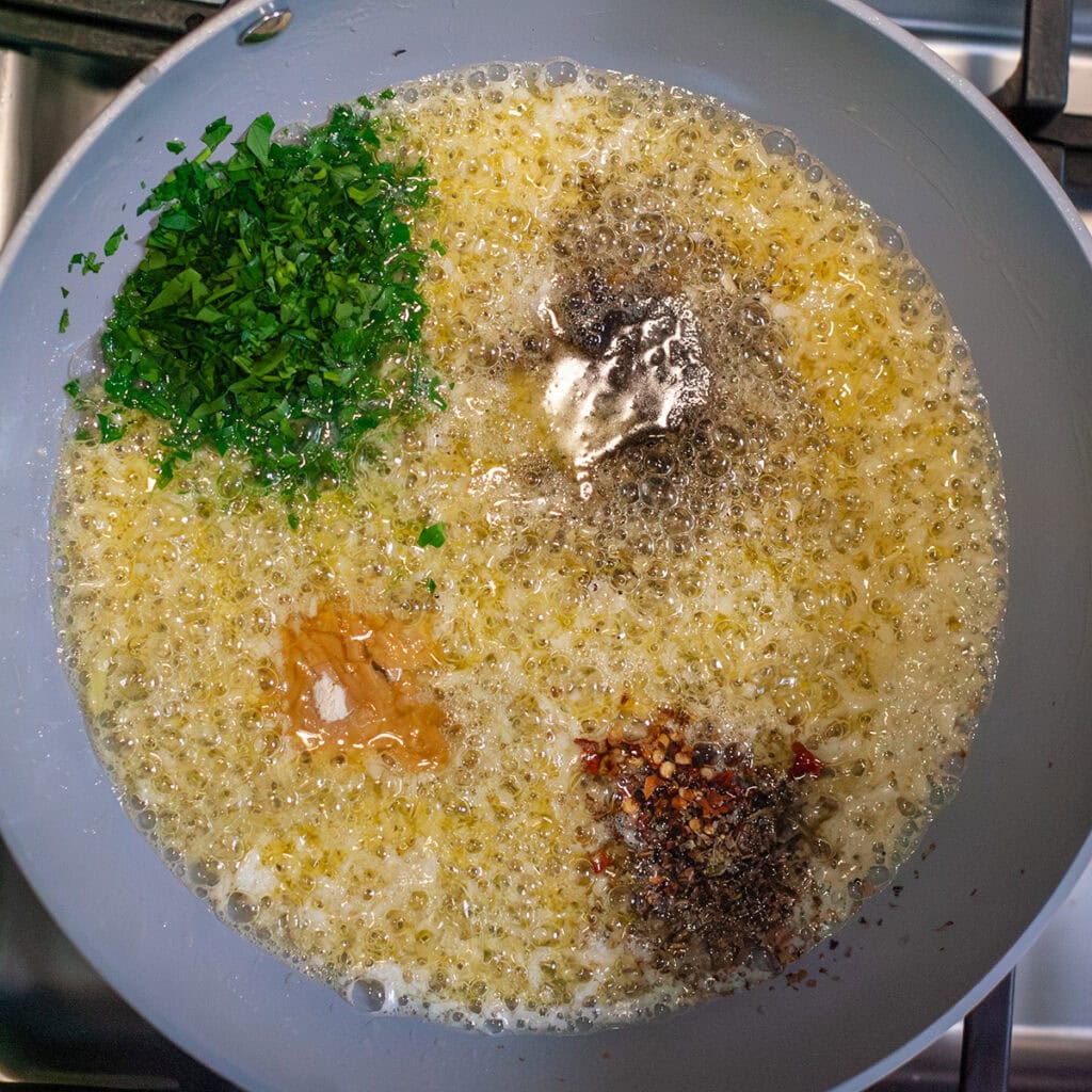 Melted butter in a skillet with herbs.