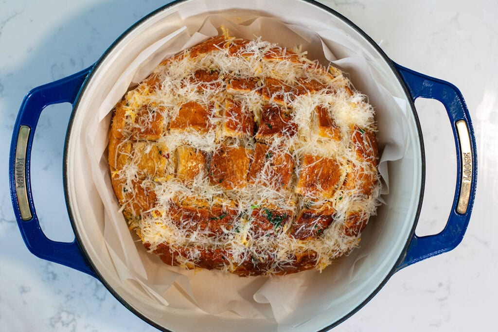 Stuffed garlic bread on parchment paper in a dutch oven.