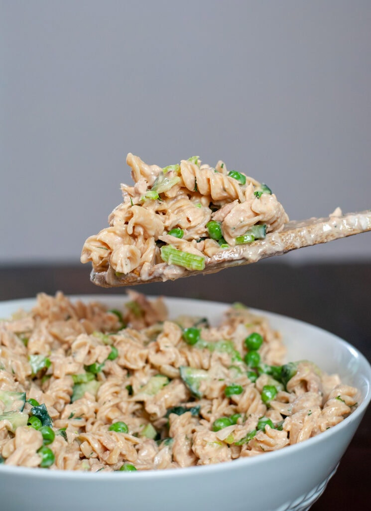 Pasta salad with sauce, vegetables and lemon juice mixed in a bowl.