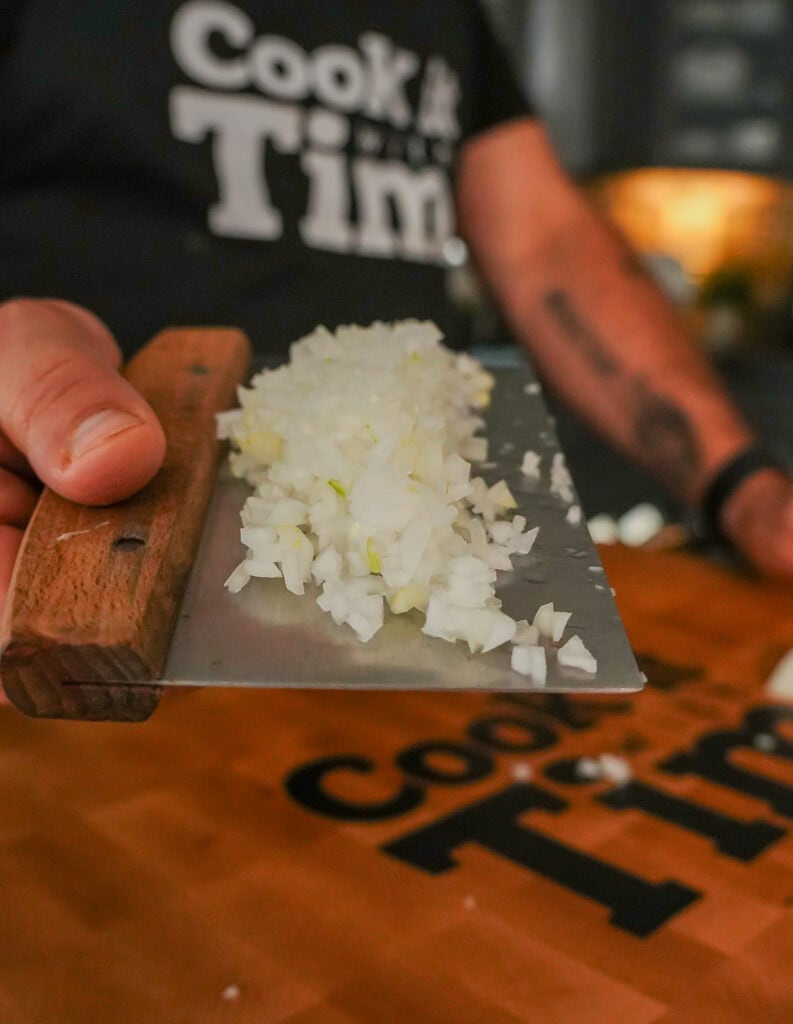 Finely diced onion on a bench scraper.