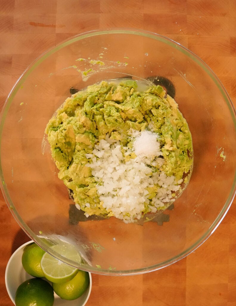 A top view of avocado, salt and onion in a bowl