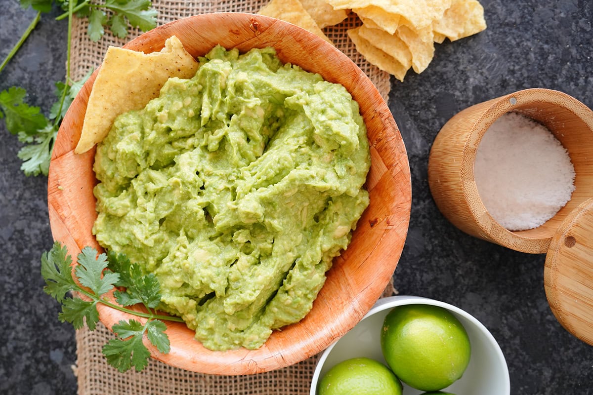 A top view of 4 ingredients guacamole in a bowl with chips.