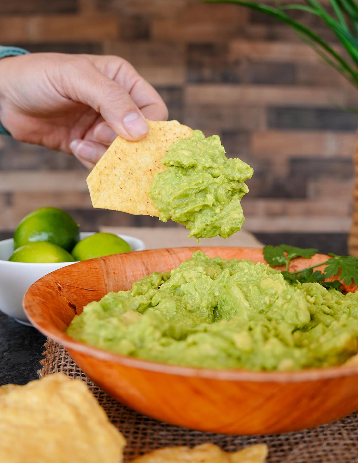A chip showing a scoop of 4-ingredient guacamole in a bowl.