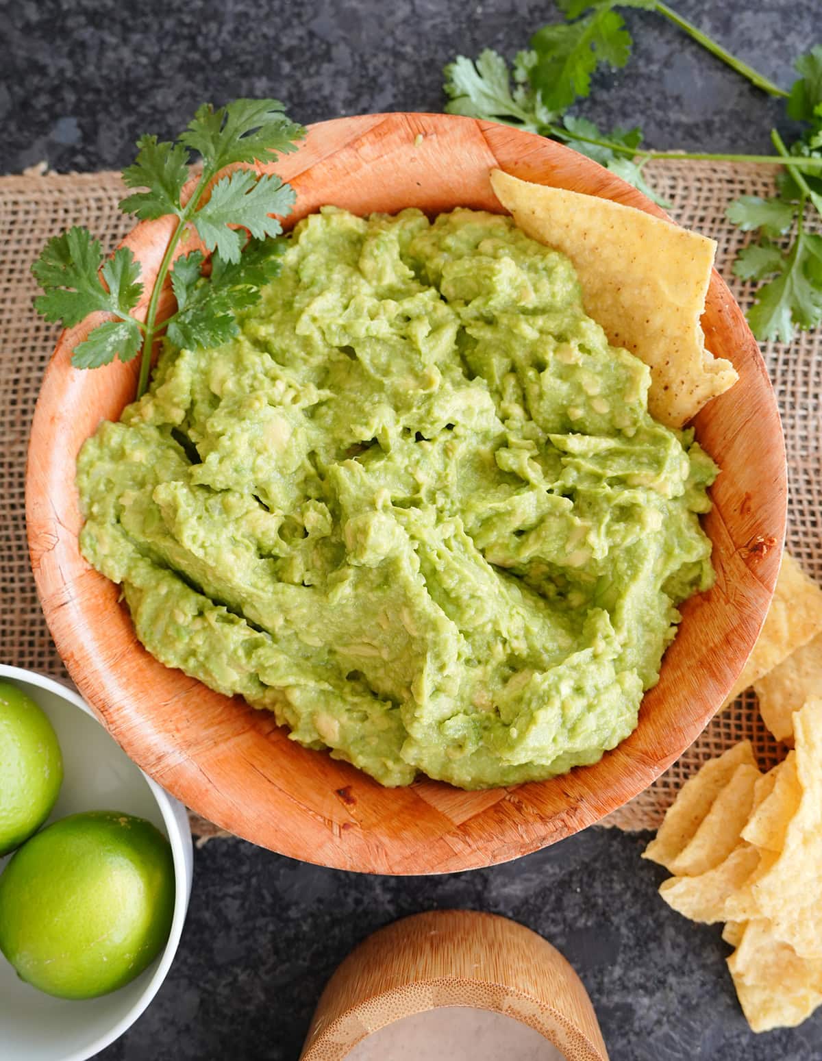A bowl of guacamole with a chip in it.