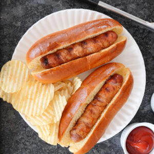 Hot dogs wrapped in bacon with potato chips.