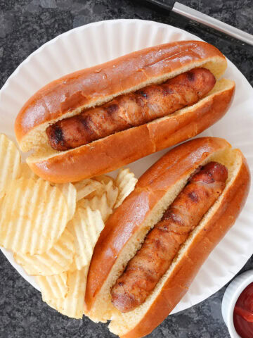 Hot dogs wrapped in bacon with potato chips.