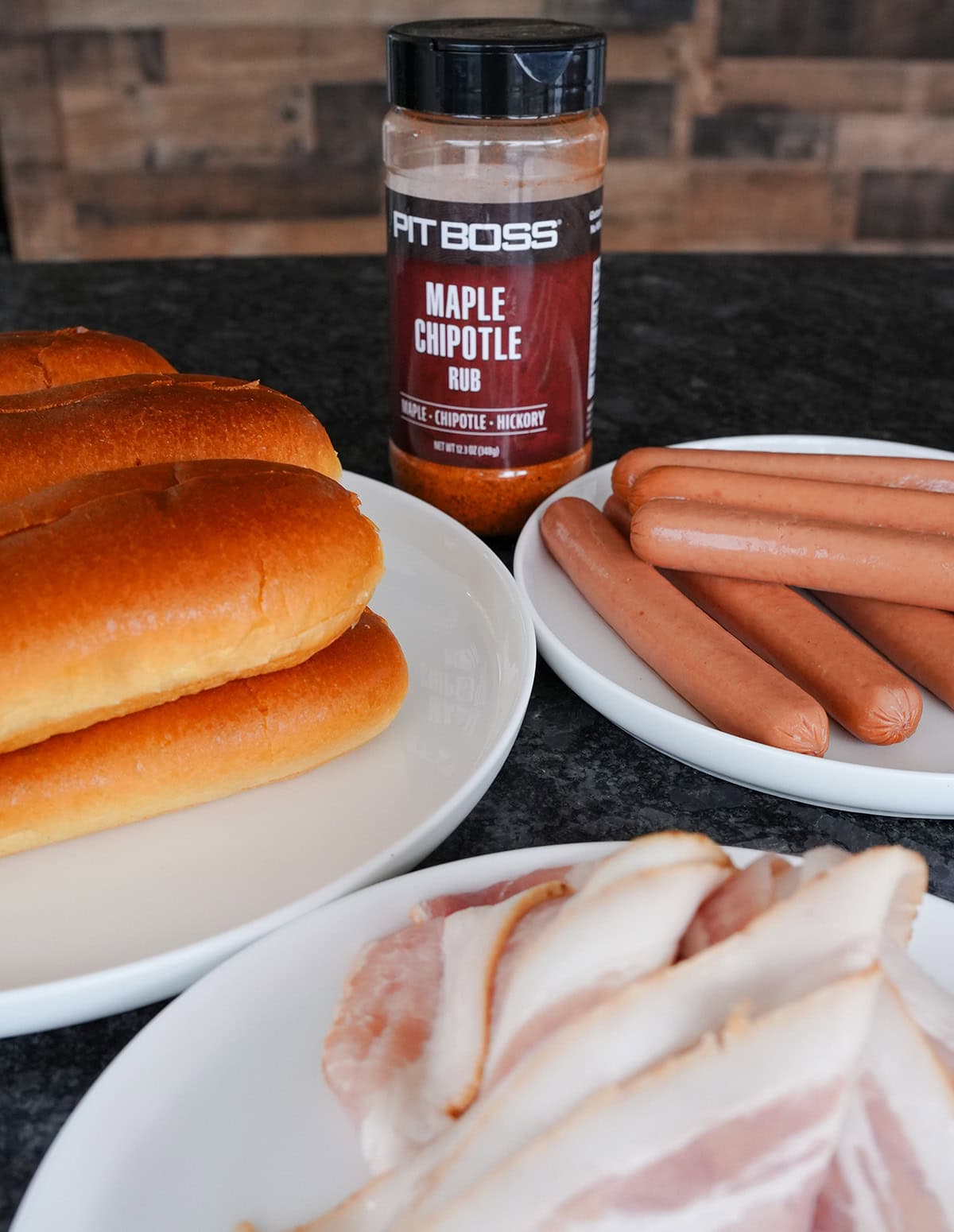 Hot dogs, buns and bbq seasoning on a counter.