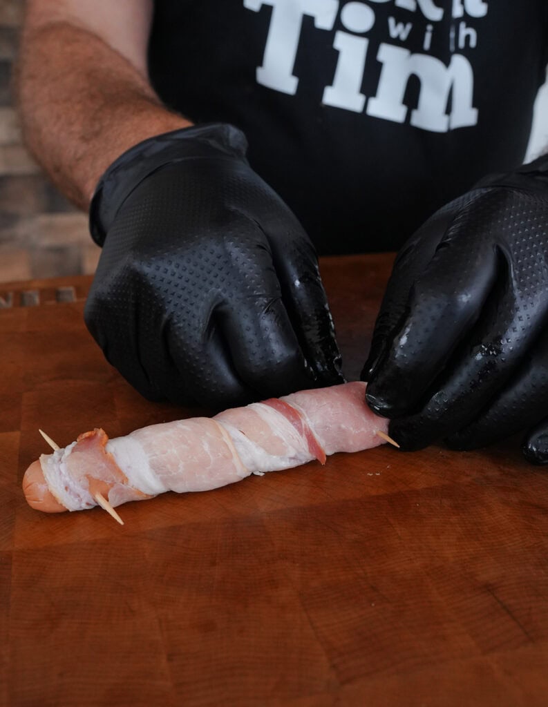 Close up of wrapped hot dog with a toothpick at end.