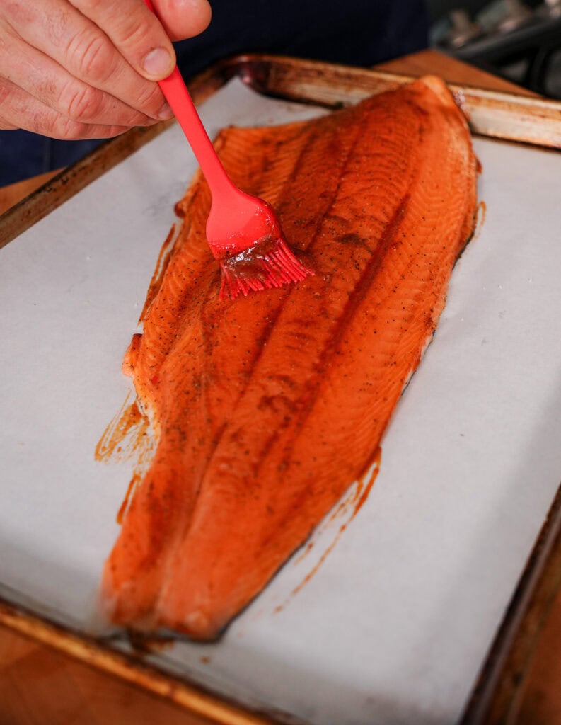 A full piece of Barbecue Salmon being basted with BBQ sauce.